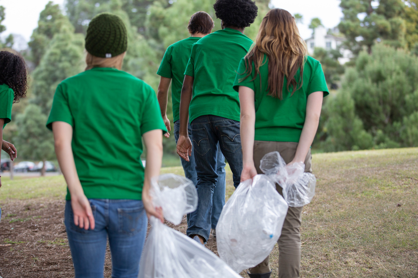 Young volunteers with garbage bags picking up litter in park